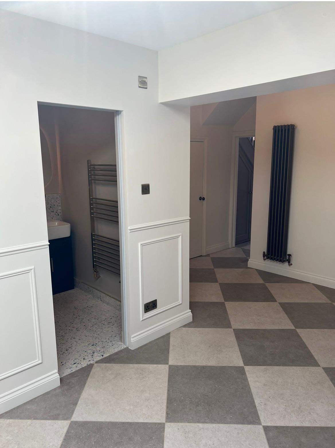 Refurbished hallway with wall panelling and large chequerboard floor tiles