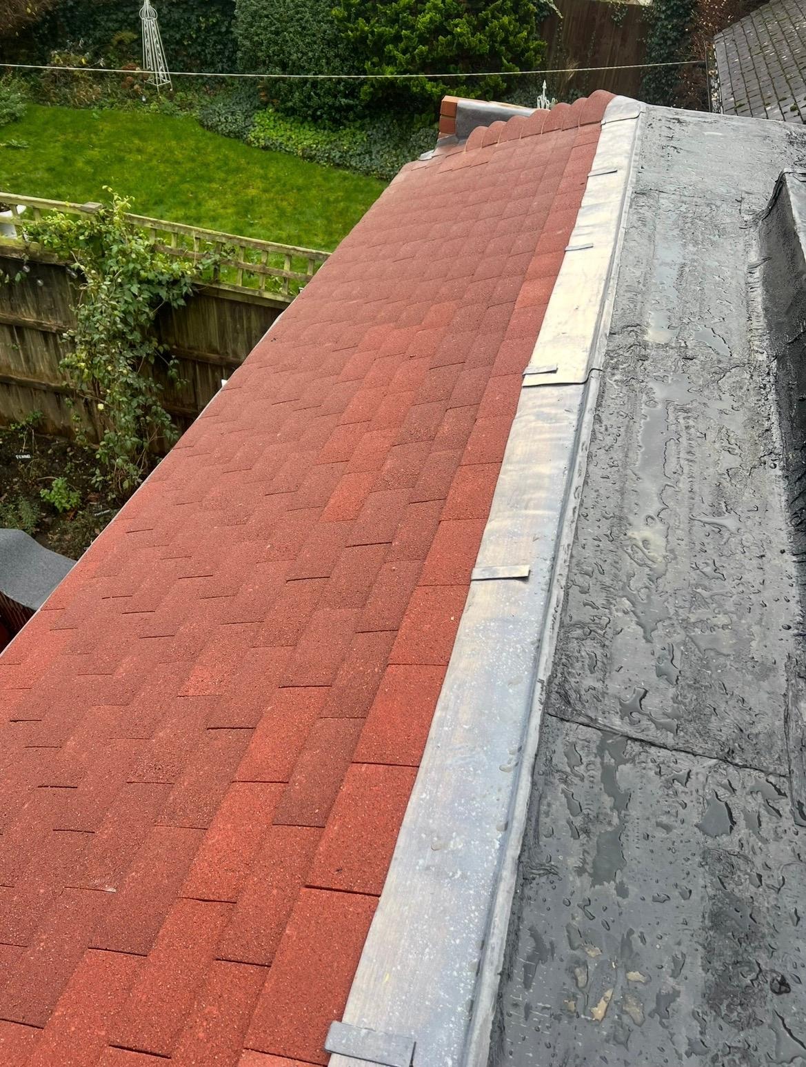 New roof tiles meeting a flat roof with lead flashing on a completed roofing job