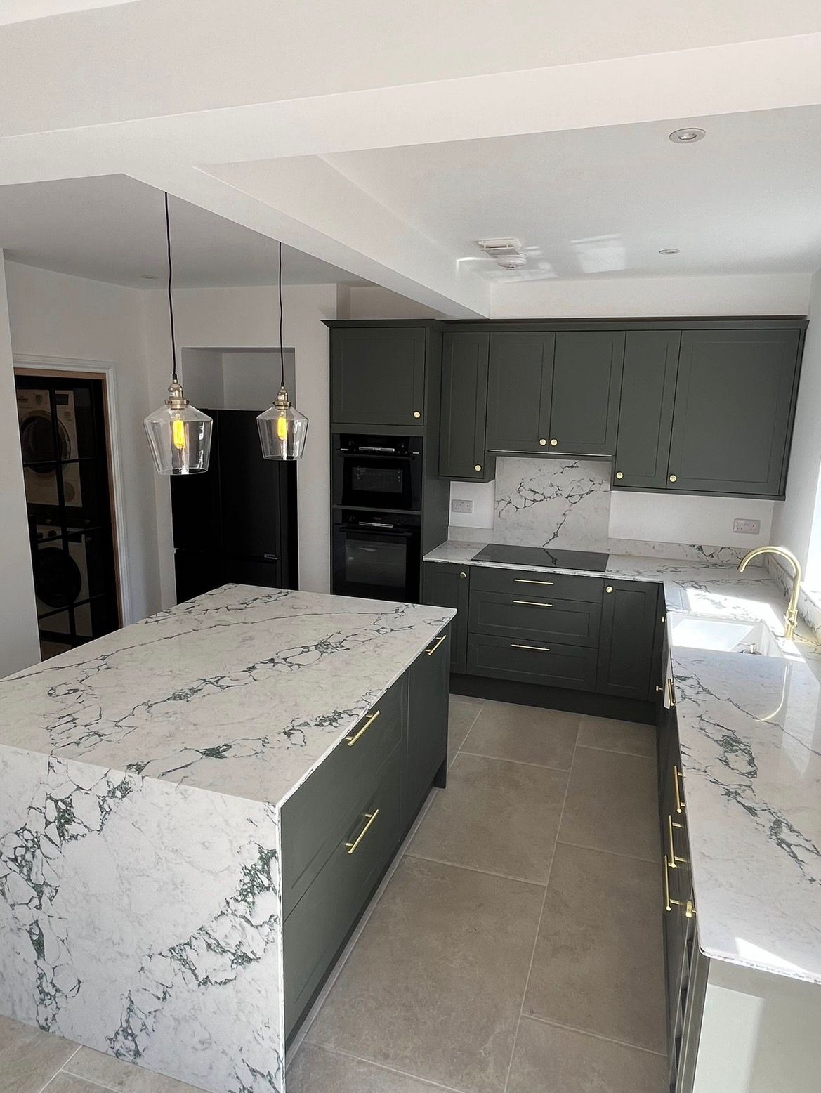 Refurbished kitchen with marble-effect worktops and pendant lighting