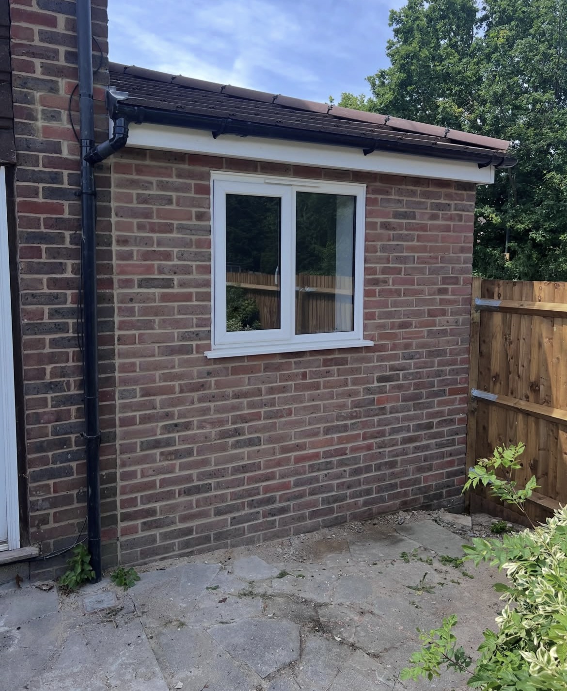 Completed brick side extension in Sidcup with white-framed window and guttering