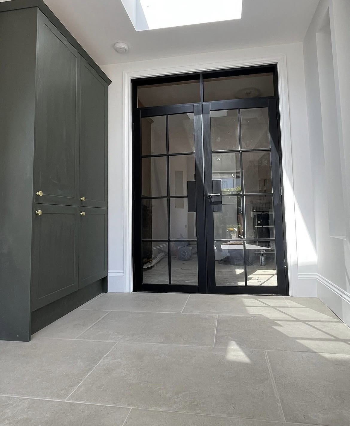 Refurbished interior with steel-look glazed doors, fitted cupboards and rooflight