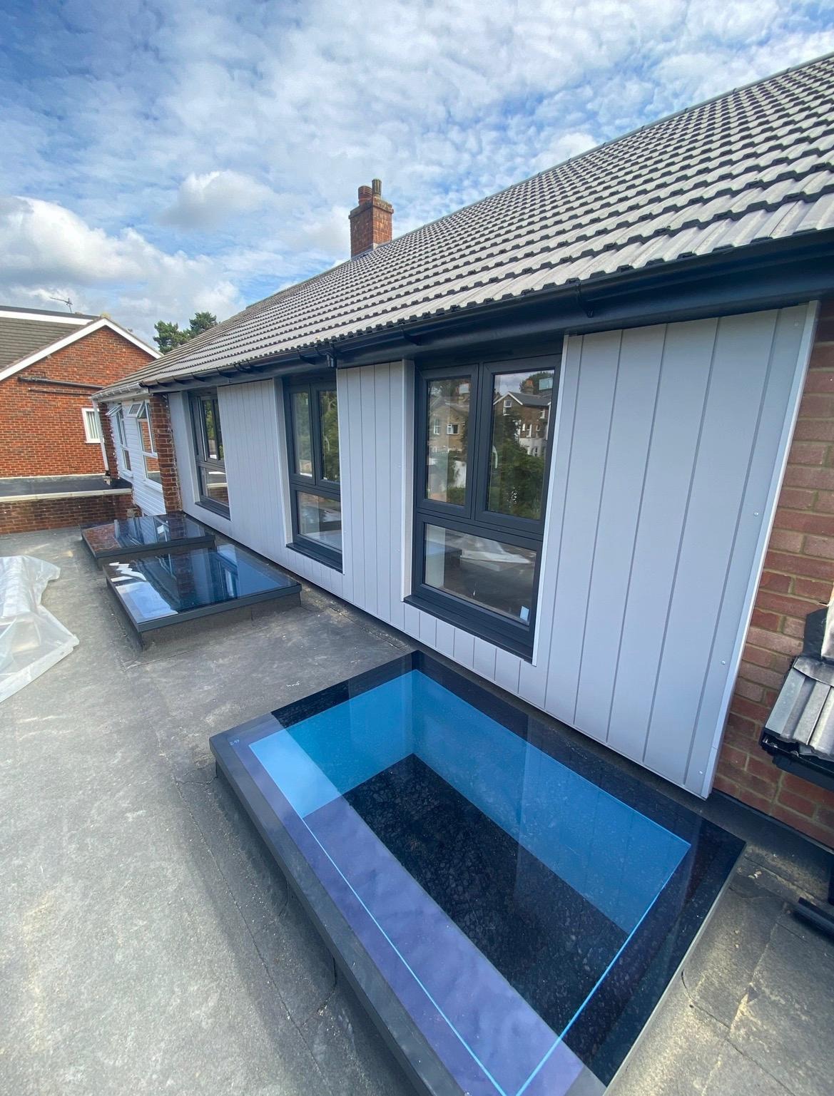 Side view of a completed roof extension with pale cladding and rooflights