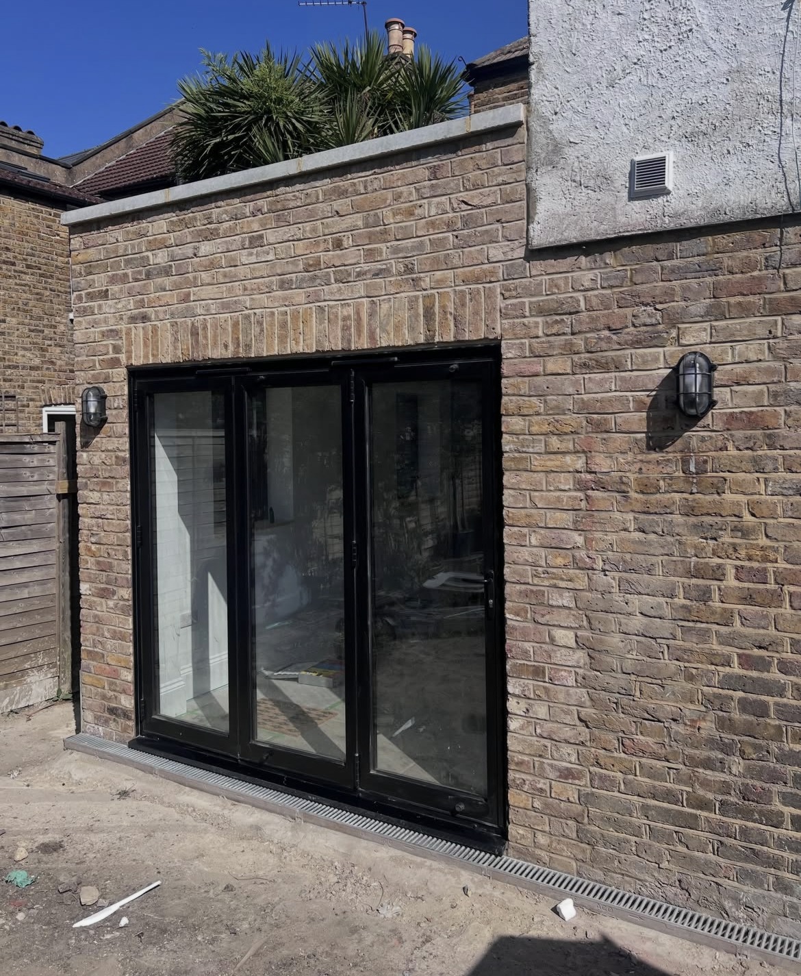 Completed brick side extension with black bifold doors and drainage channel
