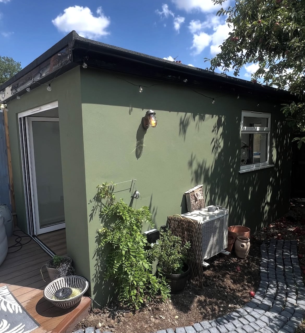 Side elevation of a finished garden outbuilding with planting and paved path