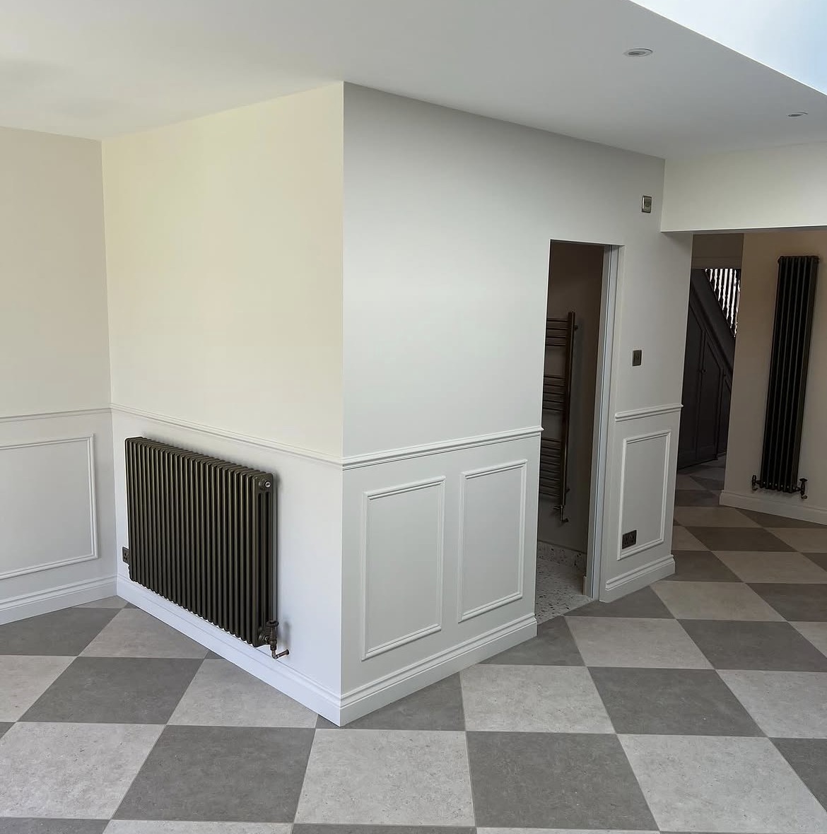 Hallway of a rear extension project with wall panelling and chequerboard tiled flooring