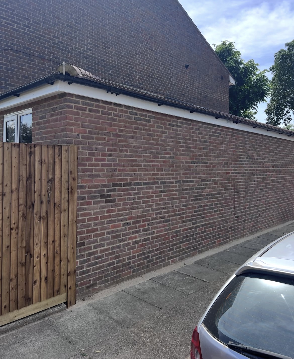Completed brick extension wall beside the pavement with a new timber gate