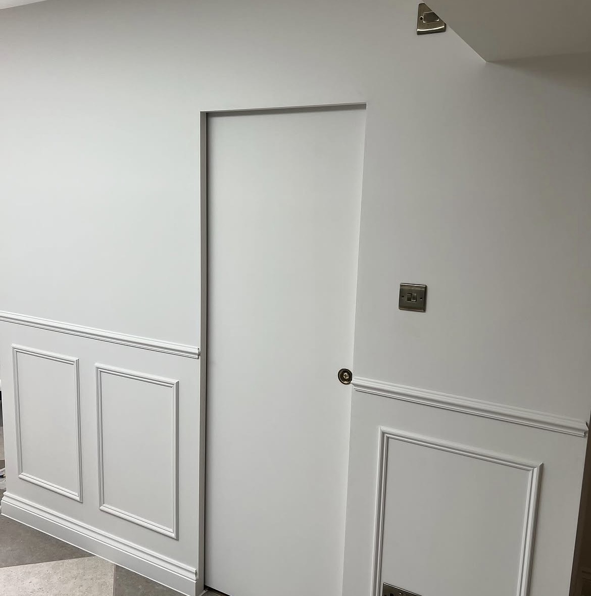 Concealed door within painted wall panelling in a completed extension