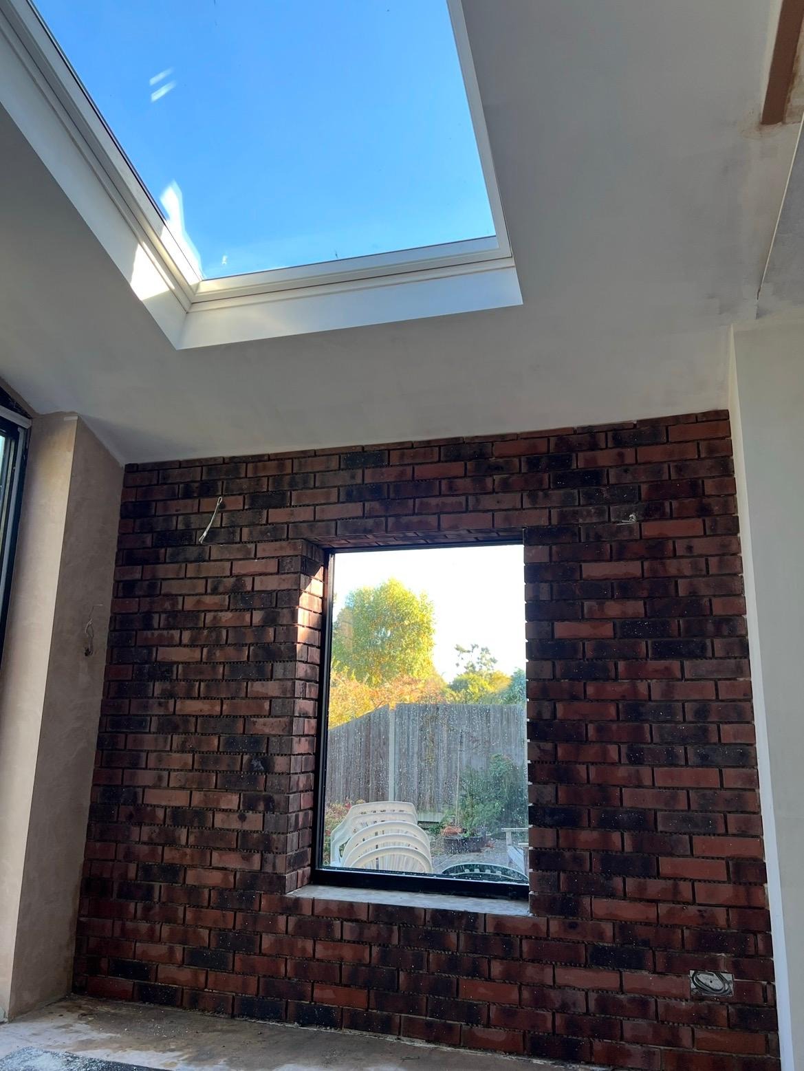 Interior of an extension under construction with rooflight opening and exposed brickwork