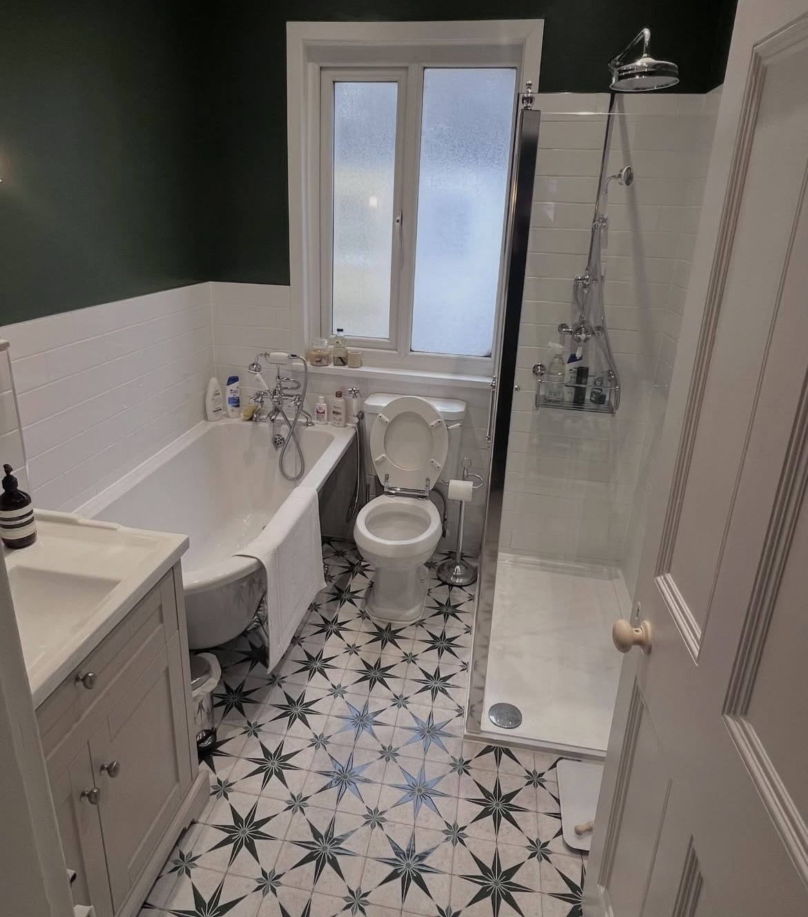 Renovated bathroom with dark green walls, white tiling and shower enclosure