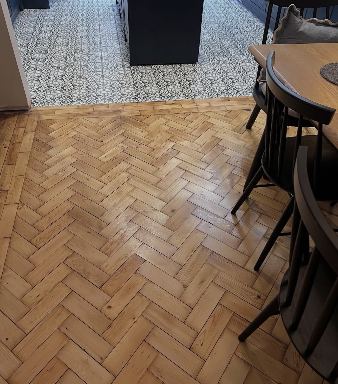 Herringbone timber flooring meeting patterned kitchen tiles in a house renovation