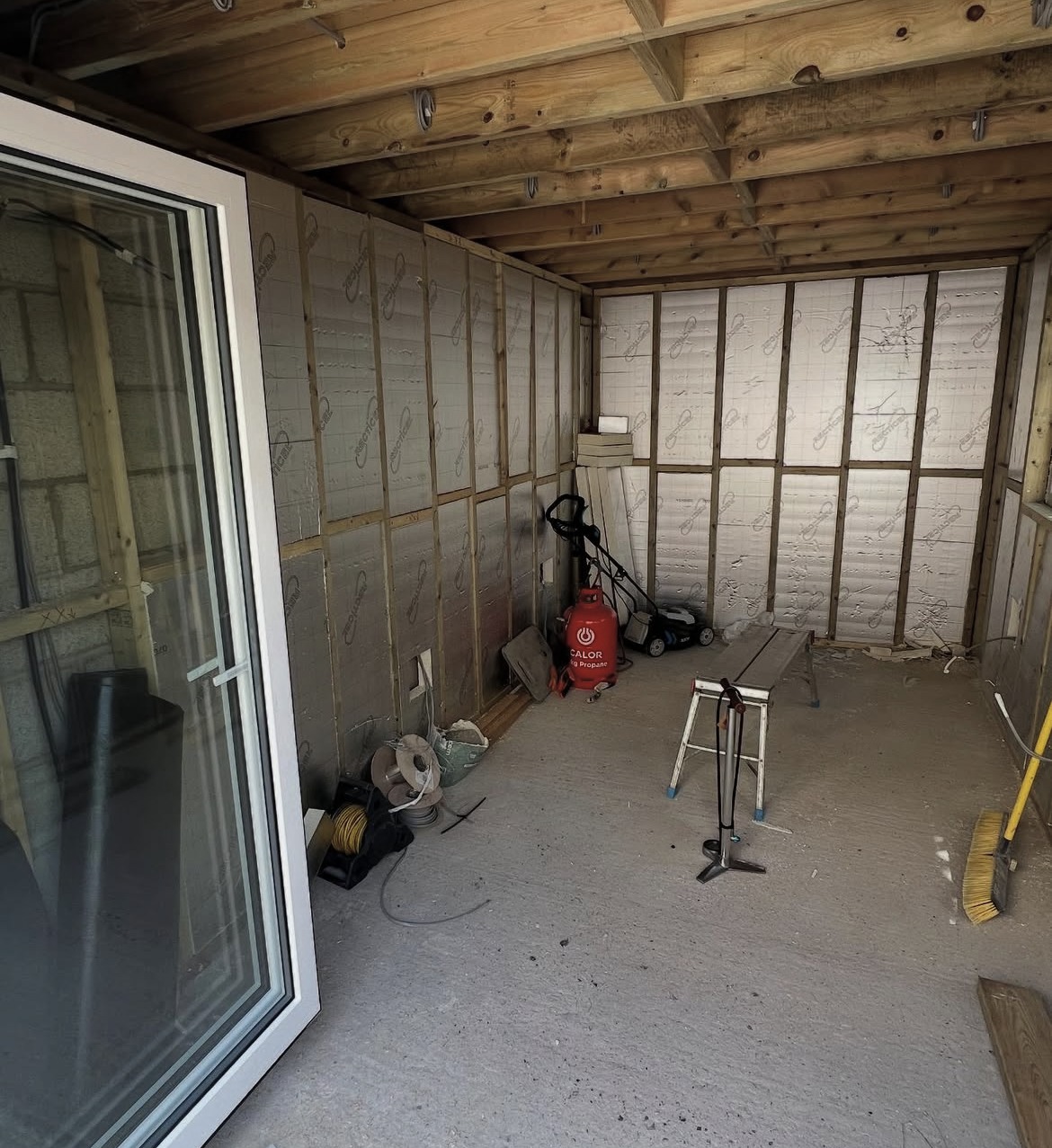 Outbuilding interior under construction with insulation and timber framing