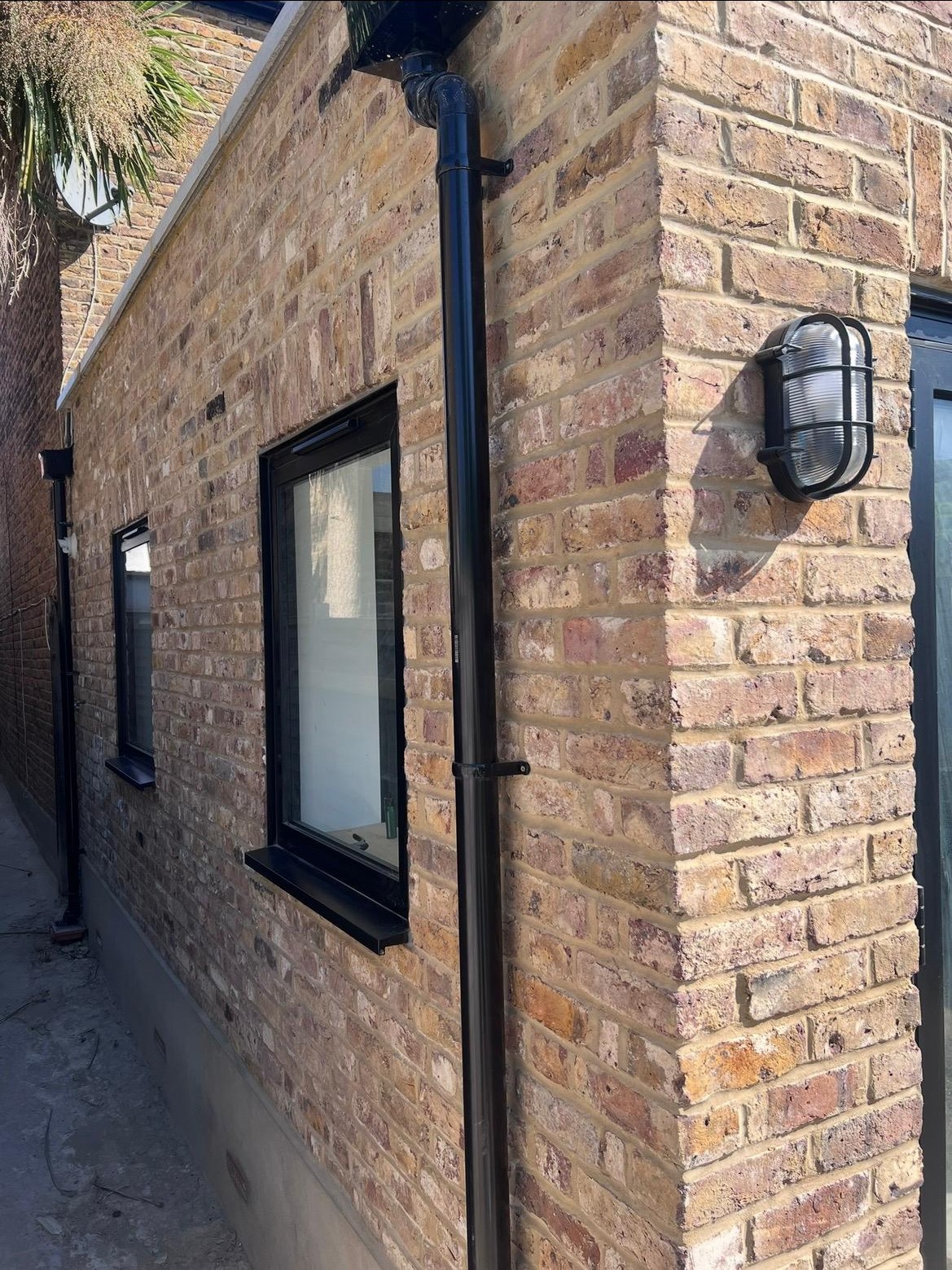 Facing brickwork on a completed house extension with black-framed windows