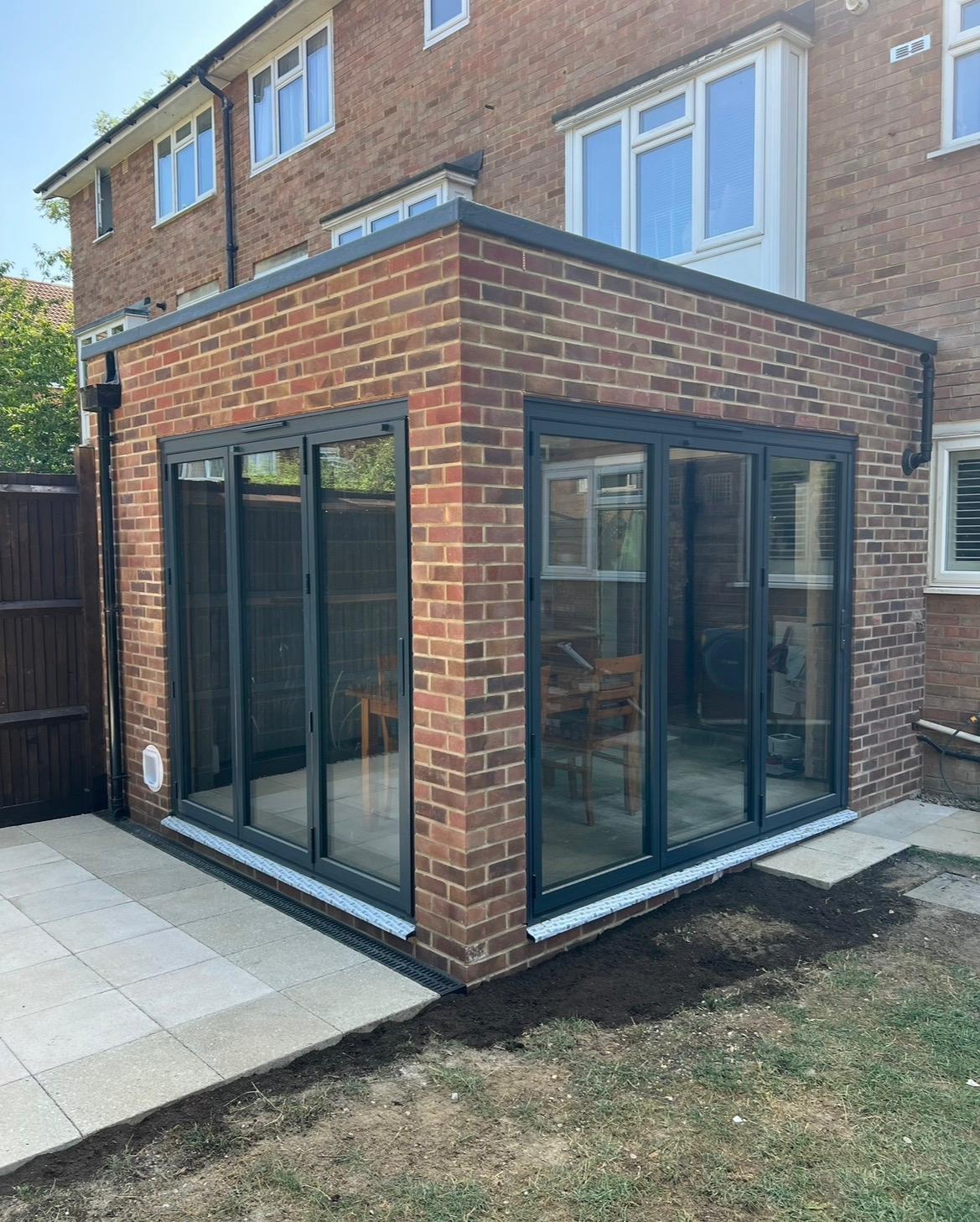 Completed brick rear house extension with dark-framed glazing and new patio