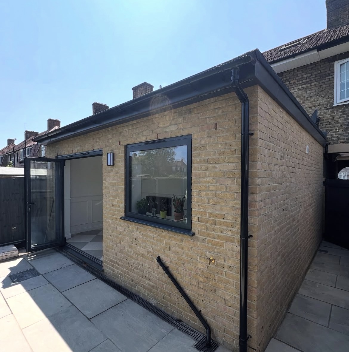 Completed single-storey yellow brick rear extension with black-framed glazed doors