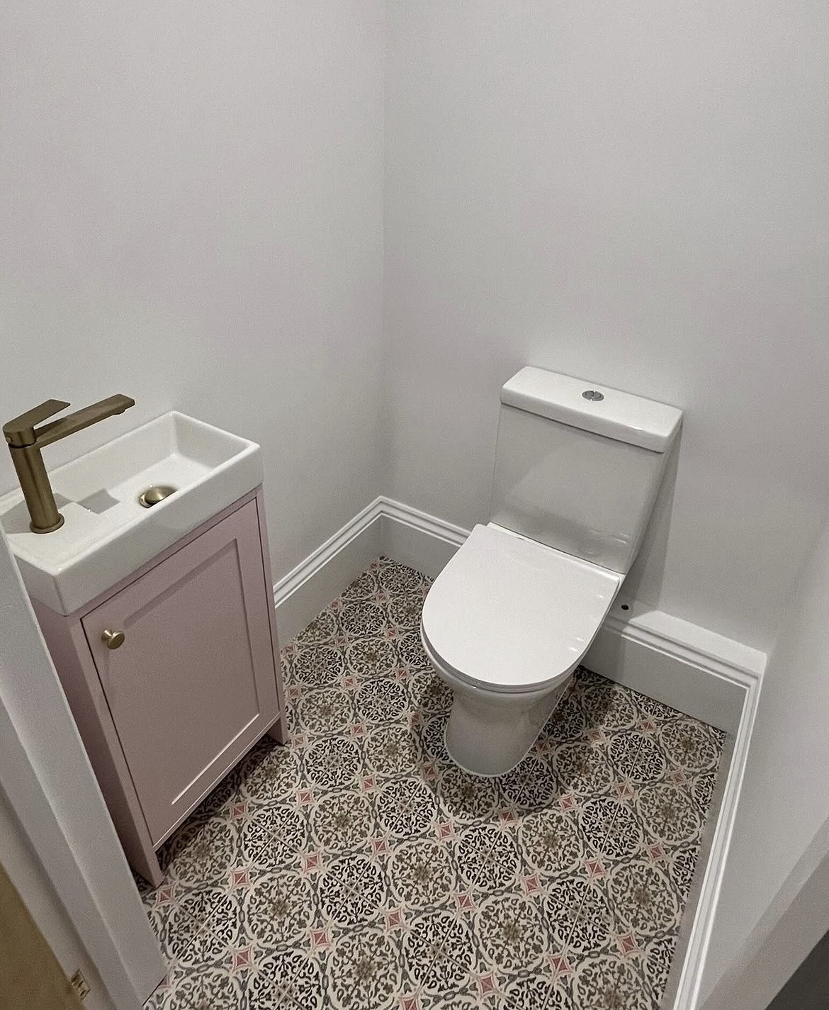 New downstairs cloakroom with patterned floor tiles and pink vanity unit