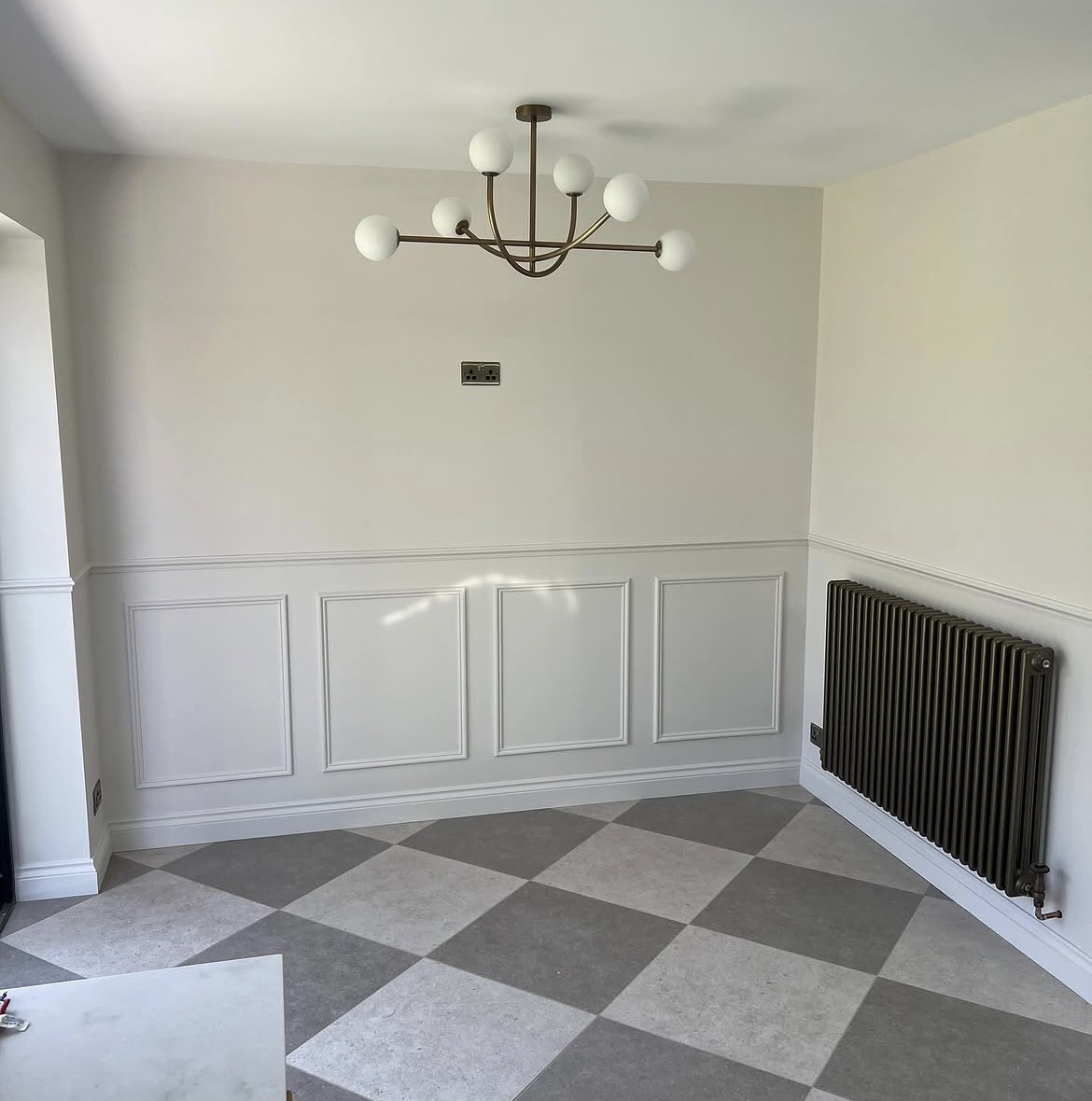 Dining area inside a finished rear extension with wall panelling and chequerboard floor tiles